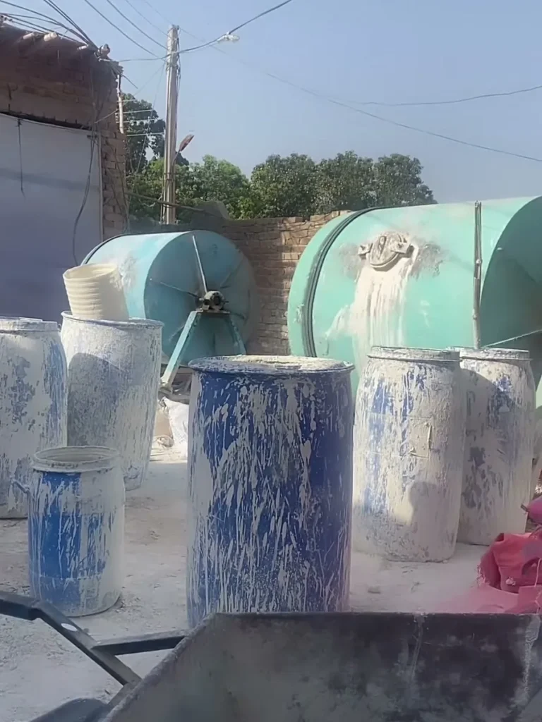 Drums of prepared clay and glaze standing in the factory yard