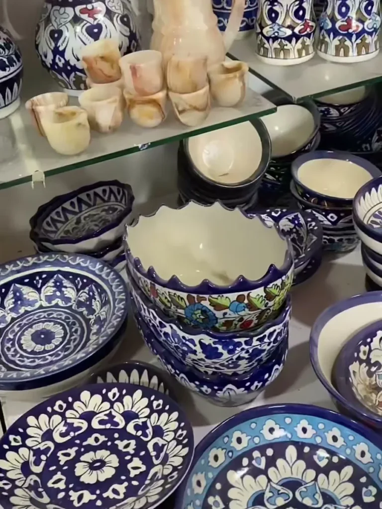 Unfired pieces standing beside finished glazed pottery in the workshop